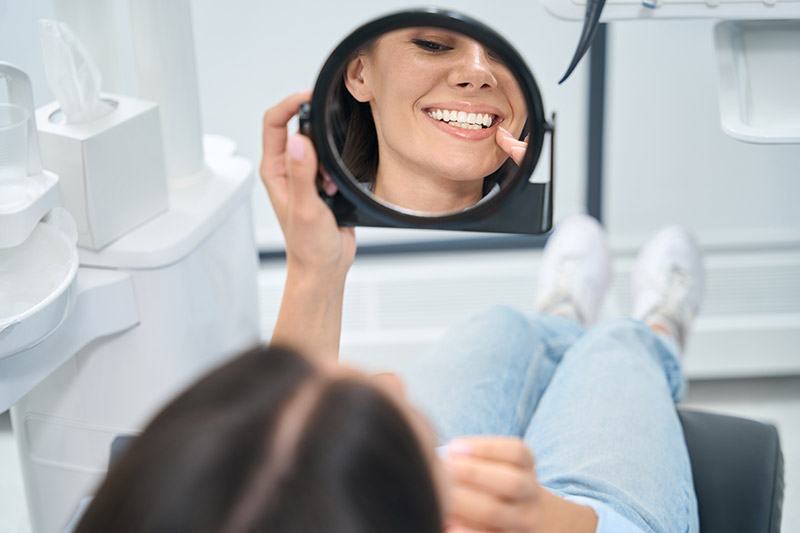Patient checking her smile in hand mirror